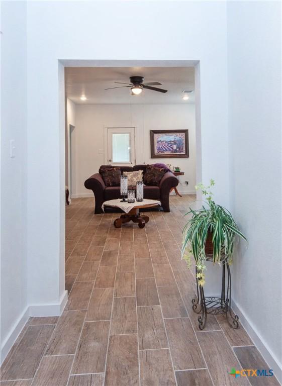 living room with light wood-type flooring, ceiling fan with notable chandelier, and sink