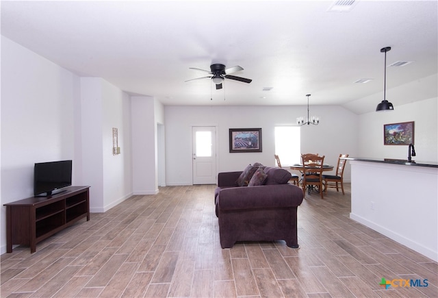 living room featuring ceiling fan with notable chandelier, light hardwood / wood-style flooring, lofted ceiling, and sink