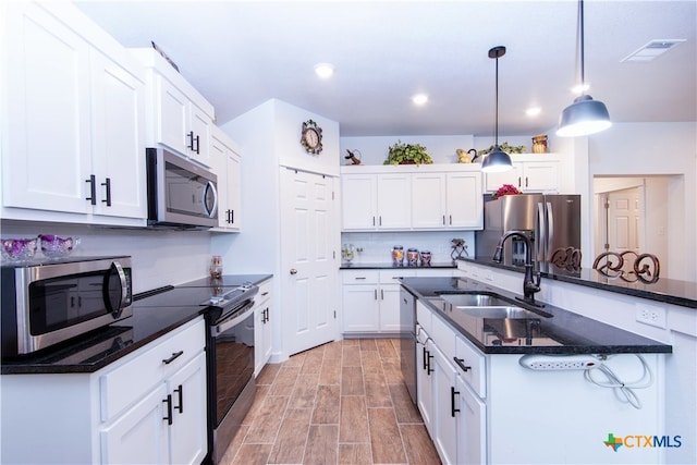 kitchen featuring stainless steel appliances, white cabinetry, hanging light fixtures, sink, and light hardwood / wood-style flooring