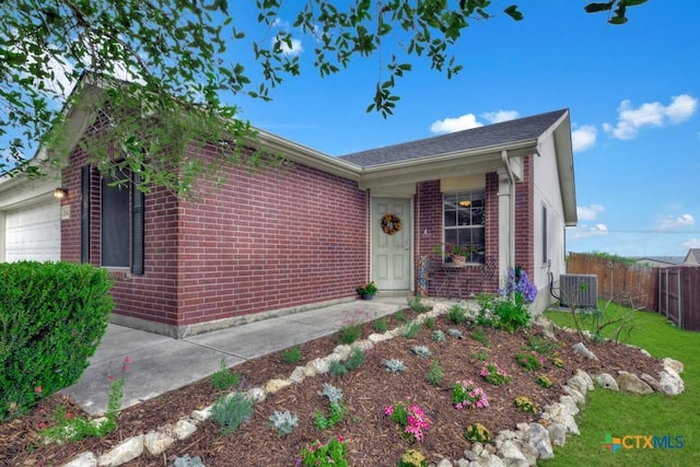 single story home featuring fence, cooling unit, a garage, and brick siding
