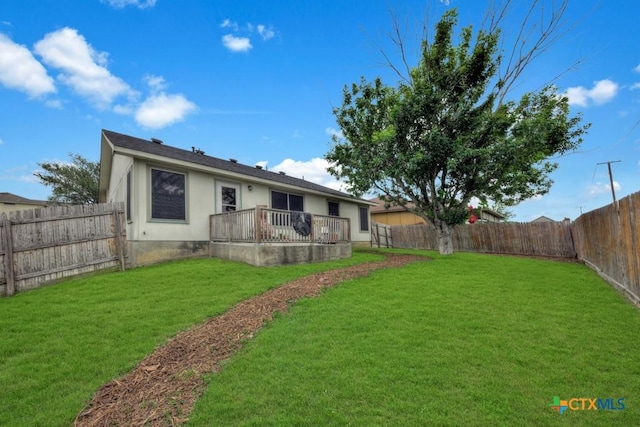 exterior space with a fenced backyard, a wooden deck, stucco siding, and a lawn