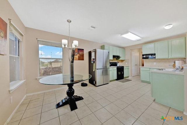 kitchen with light tile patterned flooring, a notable chandelier, a sink, backsplash, and black appliances