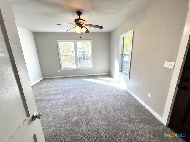 carpeted empty room with a wealth of natural light and ceiling fan