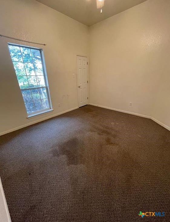 empty room featuring dark colored carpet and ceiling fan