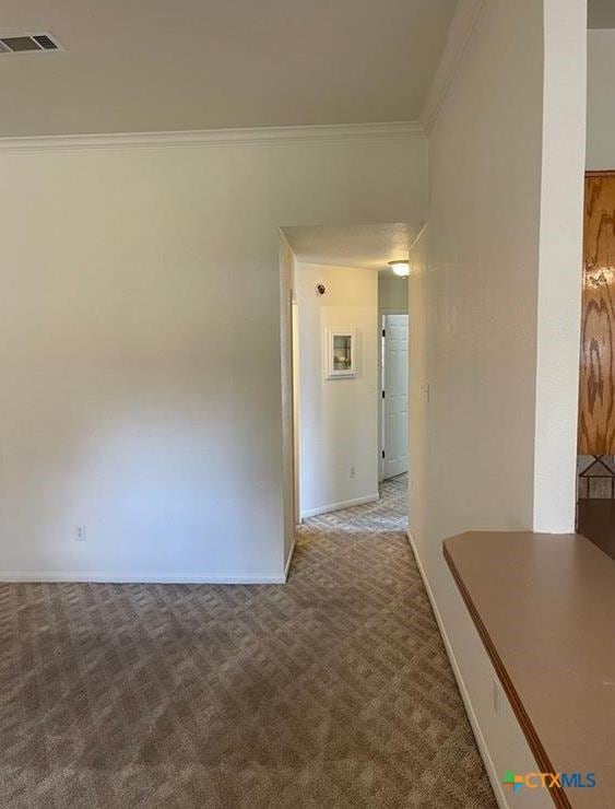 carpeted empty room featuring crown molding