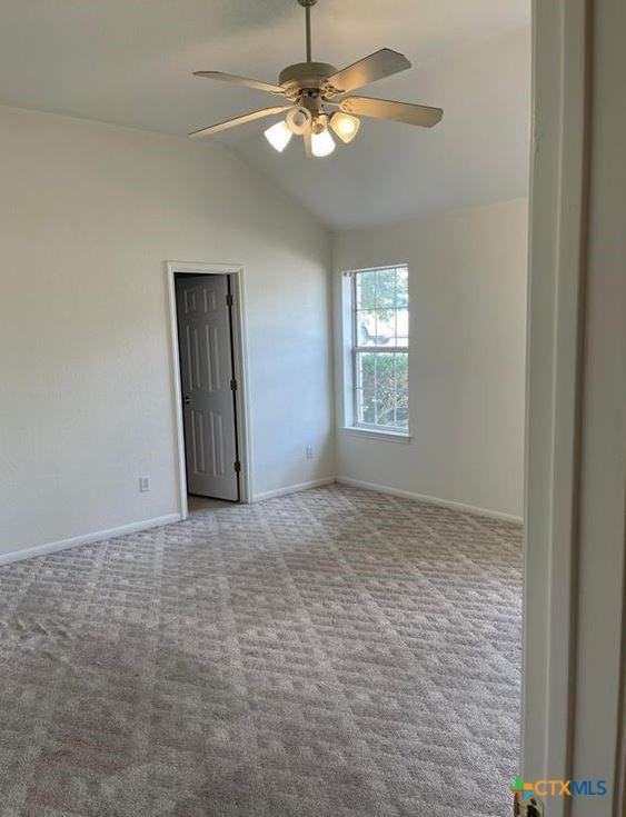 empty room featuring light carpet, lofted ceiling, and ceiling fan