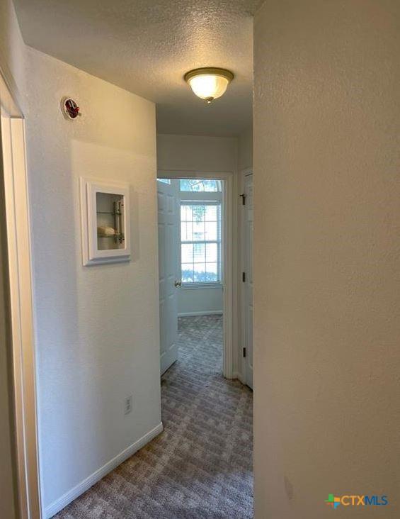 hall featuring dark colored carpet and a textured ceiling