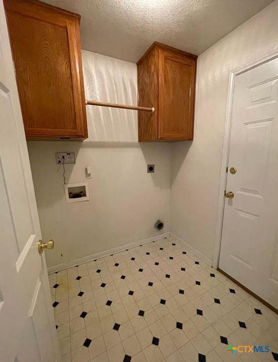 washroom featuring hookup for a washing machine, cabinets, a textured ceiling, and hookup for an electric dryer