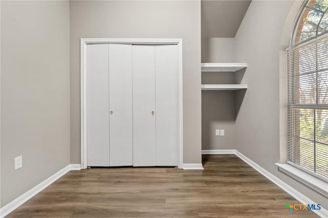 unfurnished bedroom with hardwood / wood-style floors, a closet, and multiple windows