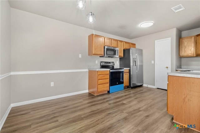 kitchen featuring hardwood / wood-style floors, decorative light fixtures, and stainless steel appliances