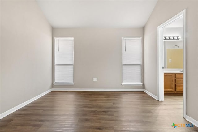 unfurnished bedroom featuring dark wood-type flooring and ensuite bath