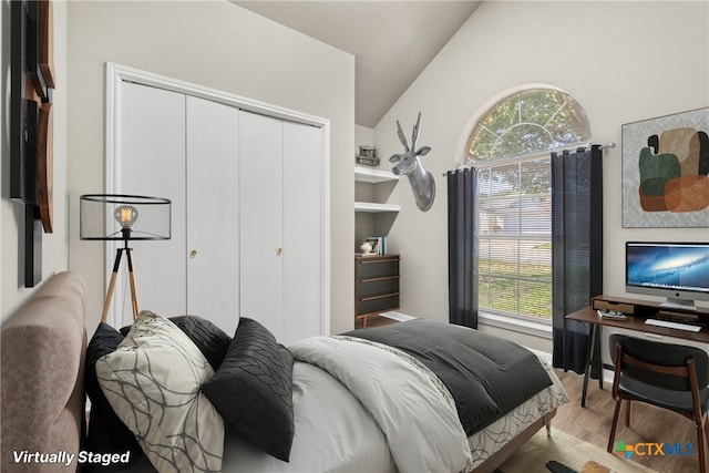 bedroom featuring light wood-type flooring, a closet, and lofted ceiling