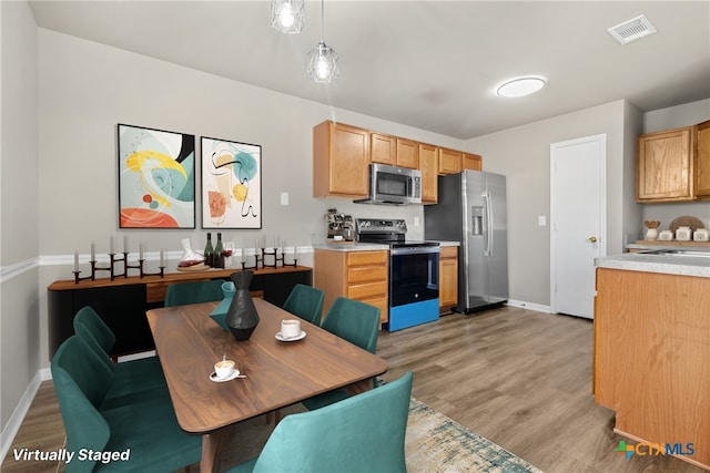 kitchen with pendant lighting, stainless steel appliances, and light hardwood / wood-style floors