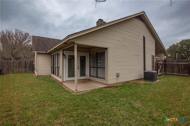 rear view of house with a fenced backyard, a lawn, and a patio