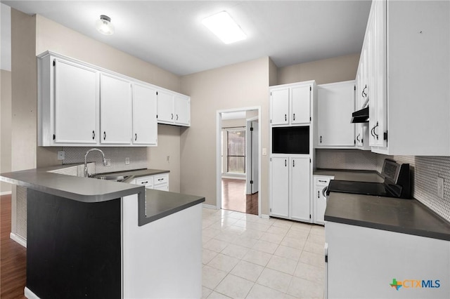 kitchen with dark countertops, range, white cabinets, and a sink