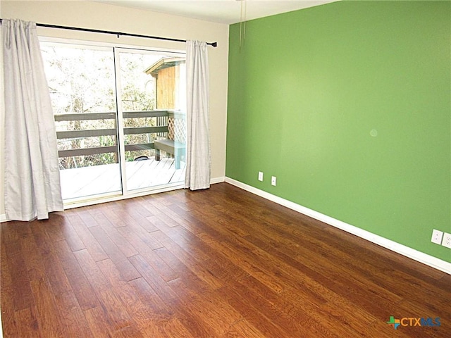 spare room featuring a wealth of natural light, baseboards, and wood finished floors