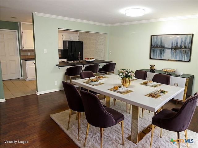 dining area featuring dark wood-type flooring, crown molding, and baseboards