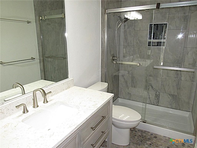 bathroom with a stall shower, vanity, and toilet