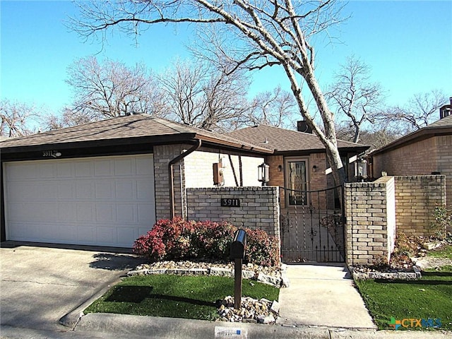 view of front of property featuring driveway, a shingled roof, an attached garage, fence, and brick siding