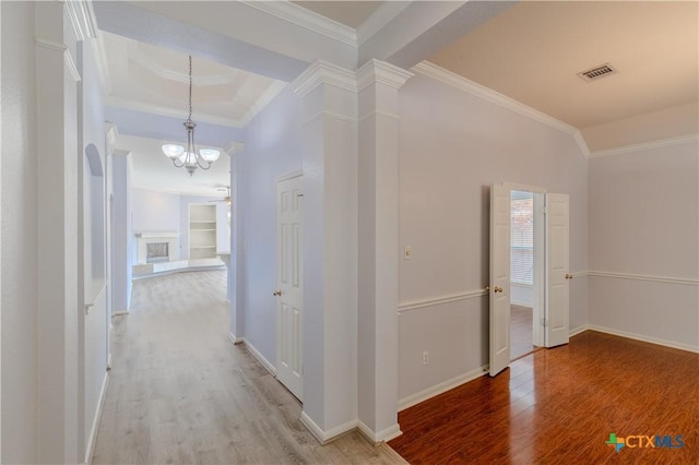 hall with visible vents, wood finished floors, decorative columns, and crown molding