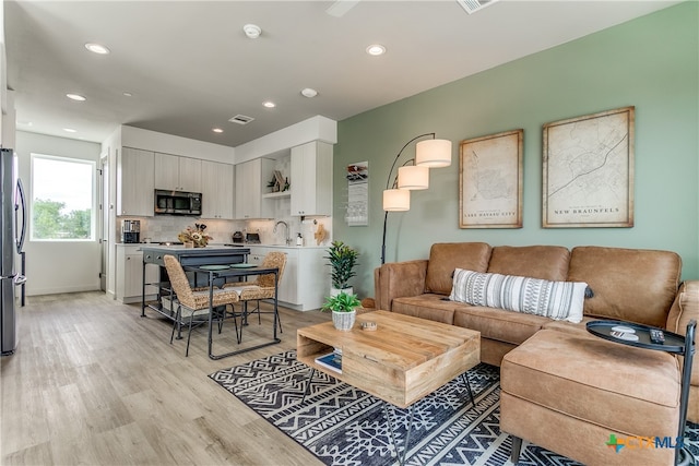 living room with light hardwood / wood-style floors and sink