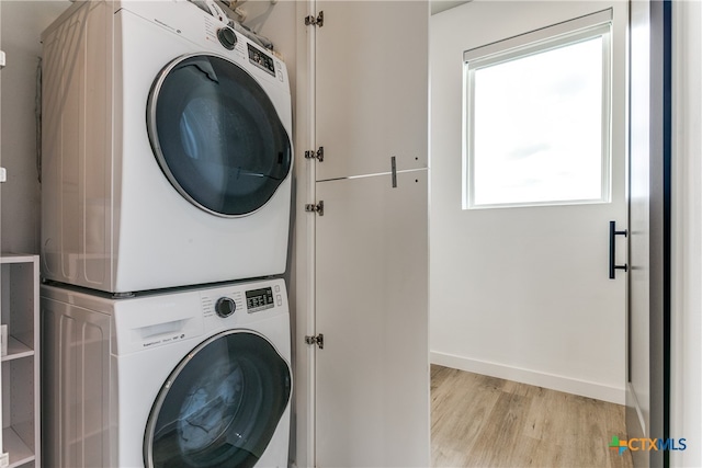 clothes washing area featuring stacked washer / dryer and light wood-type flooring