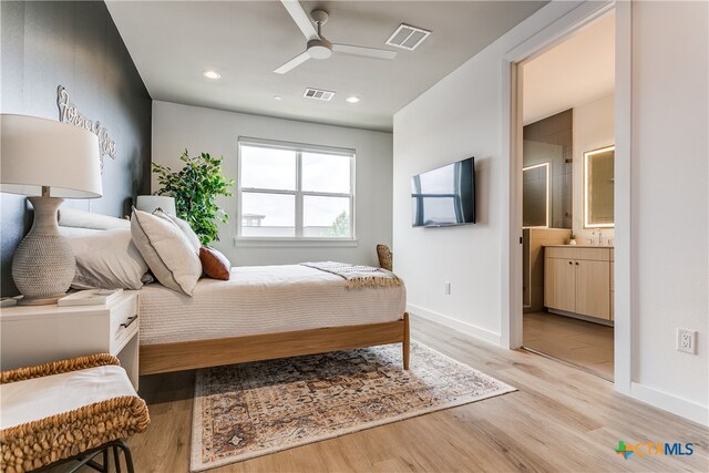 bedroom featuring light wood-type flooring, ceiling fan, and connected bathroom