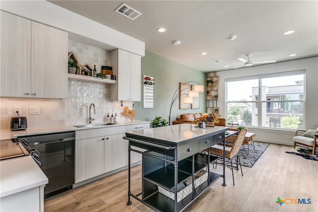 kitchen featuring sink, ceiling fan, backsplash, light wood-type flooring, and black dishwasher