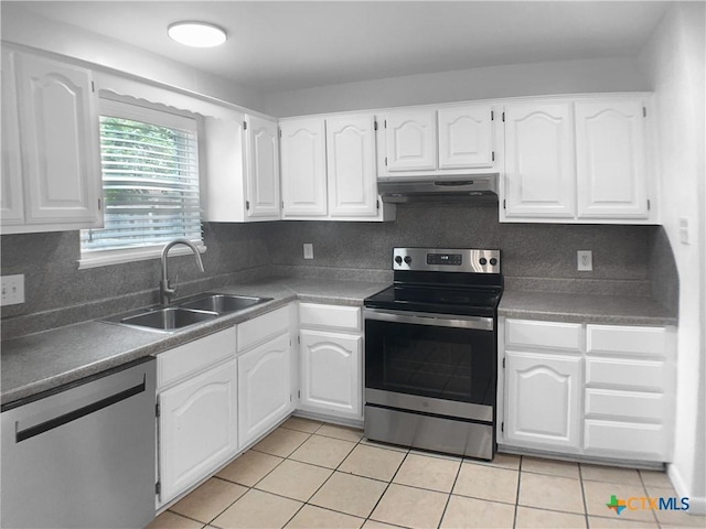 kitchen with white cabinetry, under cabinet range hood, a sink, light tile patterned floors, and stainless steel appliances