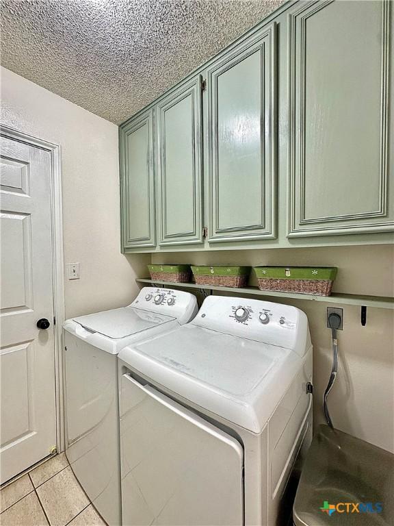 209 Westbrook Dr, Victoria, TX 77904 - washroom featuring cabinet space, separate washer and dryer, a textured ceiling, and light tile patterned floors