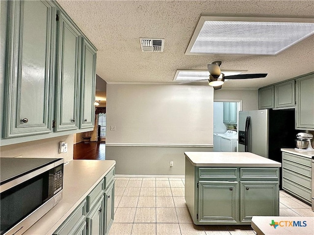 209 Westbrook Dr, Victoria, TX 77904 - kitchen featuring independent washer and dryer, green cabinetry, stainless steel appliances, ceiling fan, and light tile patterned flooring