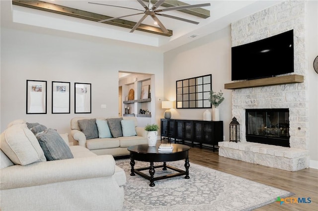 110 Terra Vista Ranch Rd, Victoria, TX 77904 - living room featuring ceiling fan, wood finished floors, a towering ceiling, a stone fireplace, and beamed ceiling