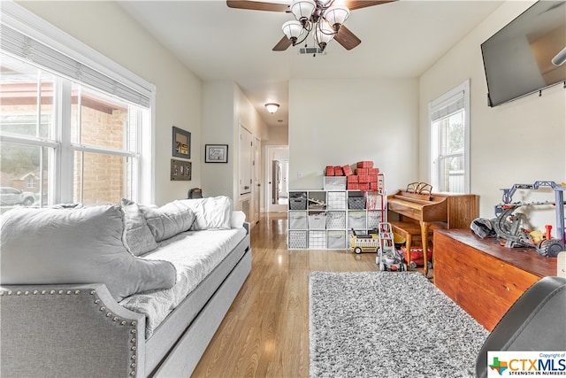 living room with ceiling fan and light hardwood / wood-style flooring