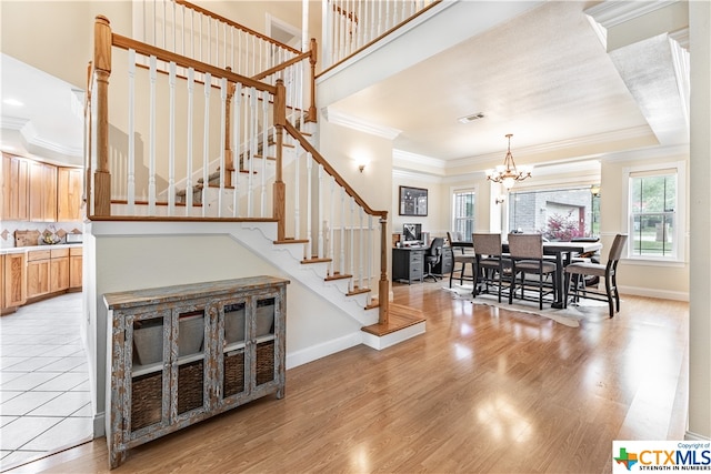 stairway with a chandelier, hardwood / wood-style flooring, and crown molding