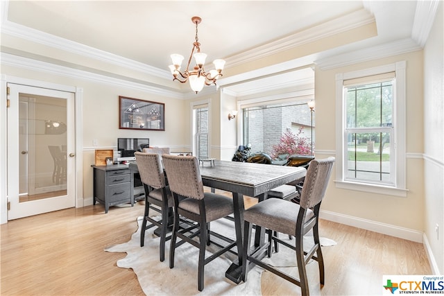 dining room featuring light hardwood / wood-style floors, a chandelier, crown molding, and a tray ceiling