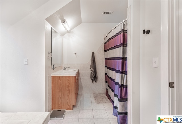 bathroom featuring walk in shower, tile patterned flooring, vanity, lofted ceiling, and tile walls