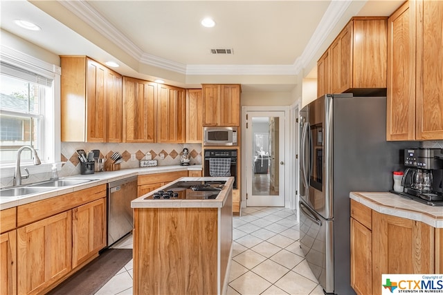 kitchen with sink, ornamental molding, light tile patterned flooring, a kitchen island, and appliances with stainless steel finishes