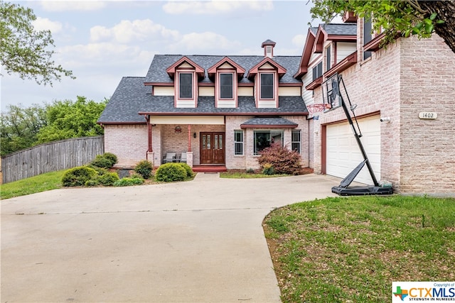 view of front of home featuring a garage, covered porch, and a front yard