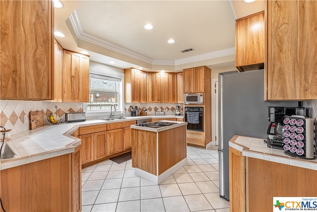 kitchen with stainless steel appliances, sink, light tile patterned floors, crown molding, and a center island