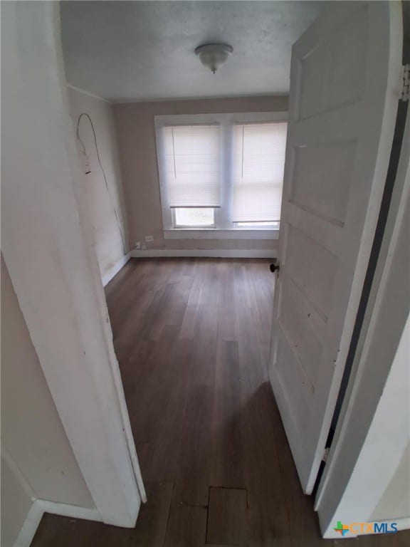 hallway featuring wood finished floors and baseboards