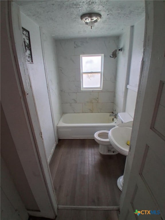 full bathroom featuring a textured ceiling, toilet, wood finished floors, a sink, and shower / bathing tub combination