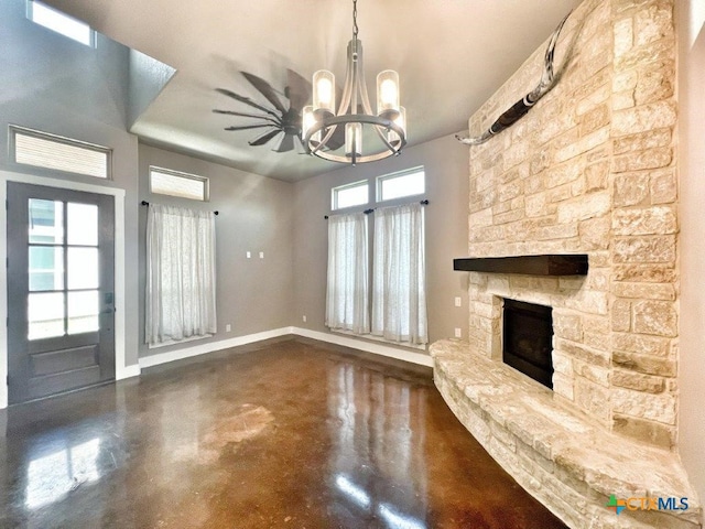 unfurnished living room featuring concrete flooring, an inviting chandelier, and a fireplace