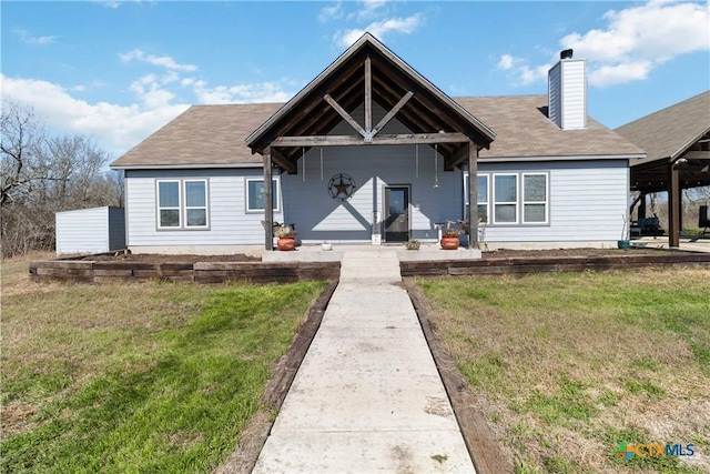 view of front of house with a porch, a chimney, and a front lawn