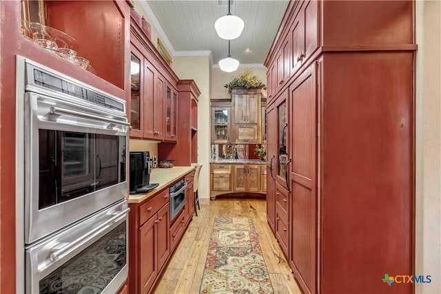 kitchen featuring double oven, light hardwood / wood-style flooring, decorative light fixtures, and ornamental molding