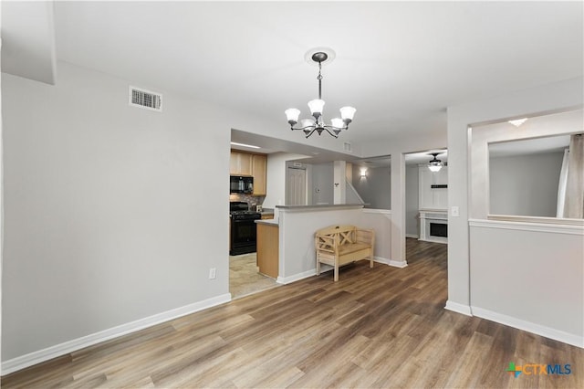 326 Trestle Tree, San Marcos, TX 78666 - kitchen featuring black appliances, a chandelier, light wood-type flooring, a ceiling fan, and a fireplace
