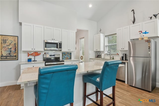 kitchen featuring a kitchen bar, appliances with stainless steel finishes, and white cabinetry