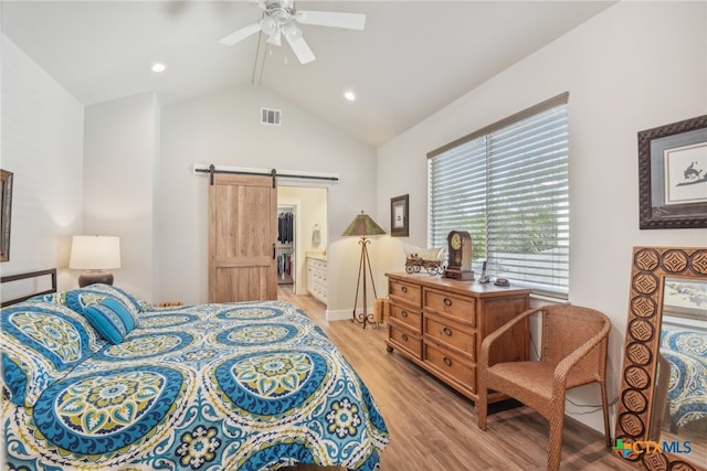 bedroom with lofted ceiling, a barn door, ceiling fan, and light hardwood / wood-style flooring