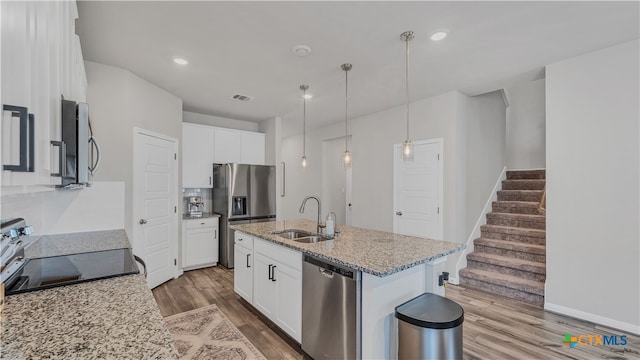 kitchen featuring stainless steel appliances, white cabinetry, sink, hardwood / wood-style flooring, and a kitchen island with sink