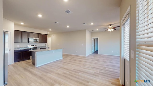 kitchen featuring appliances with stainless steel finishes, sink, a kitchen island with sink, dark brown cabinets, and light hardwood / wood-style flooring