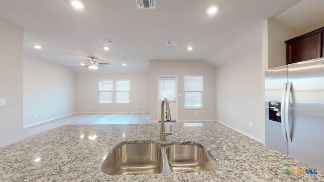 kitchen with stainless steel refrigerator with ice dispenser, ceiling fan, sink, and light stone counters